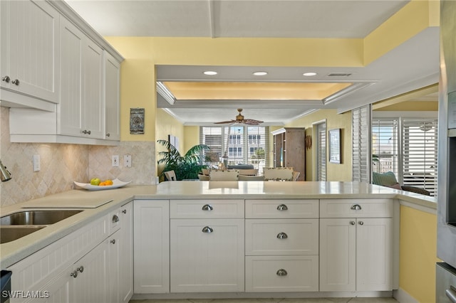 kitchen featuring white cabinetry, kitchen peninsula, and backsplash