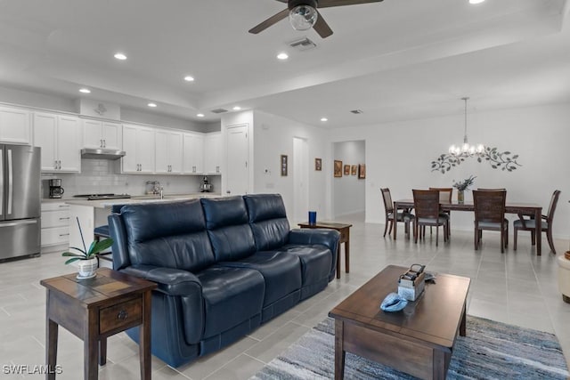 tiled living room featuring ceiling fan with notable chandelier