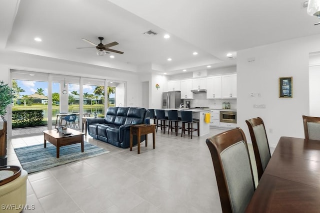 living room with ceiling fan and a tray ceiling