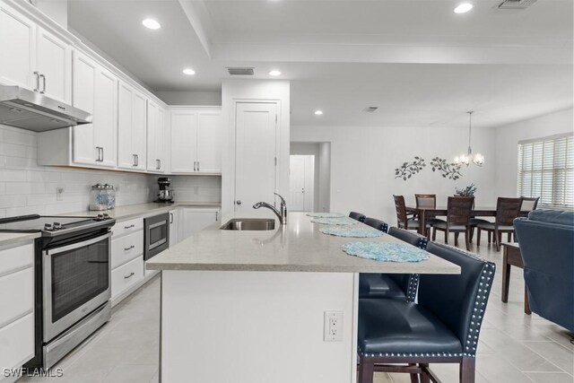 kitchen featuring a kitchen island with sink, appliances with stainless steel finishes, white cabinets, an inviting chandelier, and sink