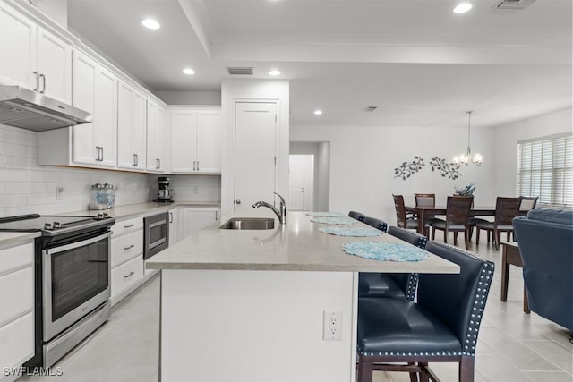 kitchen featuring a kitchen bar, sink, white cabinetry, a center island with sink, and stainless steel appliances