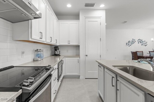 kitchen with appliances with stainless steel finishes, white cabinetry, light tile patterned flooring, and sink