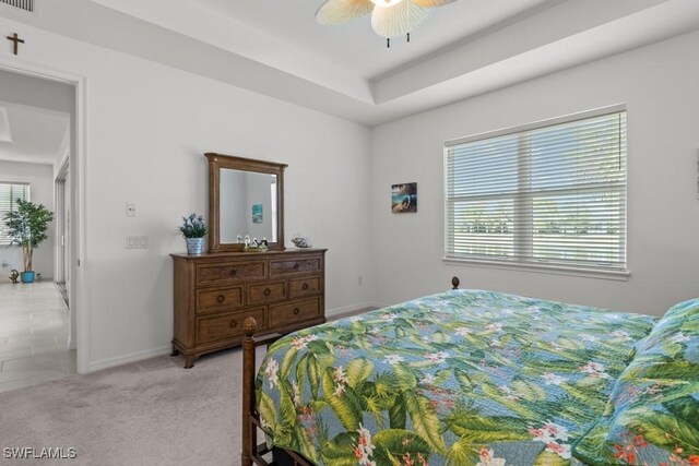 carpeted bedroom featuring ceiling fan and a tray ceiling