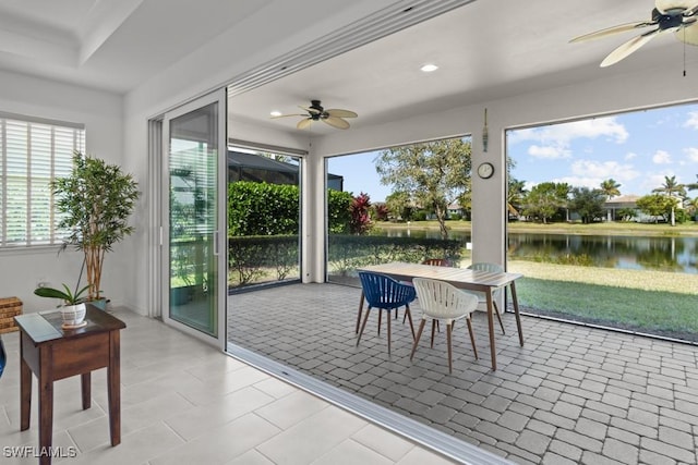 sunroom featuring ceiling fan and a water view