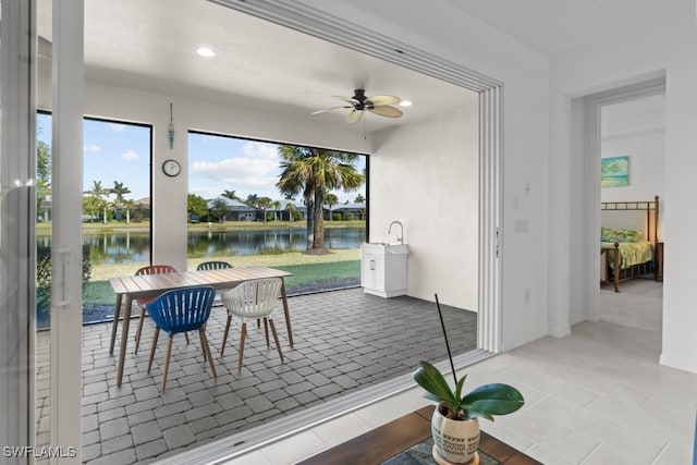 sunroom / solarium featuring ceiling fan and a water view