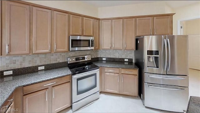 kitchen with tasteful backsplash, stainless steel appliances, and dark stone countertops