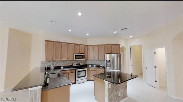 kitchen with appliances with stainless steel finishes, a kitchen breakfast bar, decorative backsplash, sink, and kitchen peninsula