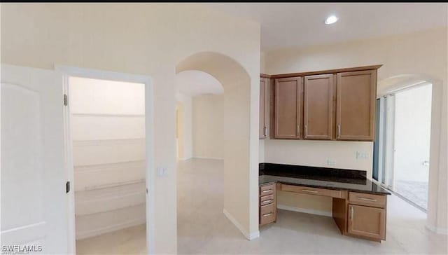 unfurnished office featuring built in desk and dark stone counters