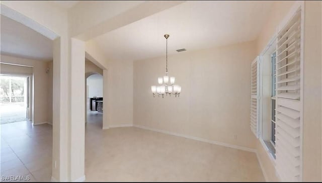 empty room with light tile patterned flooring and an inviting chandelier