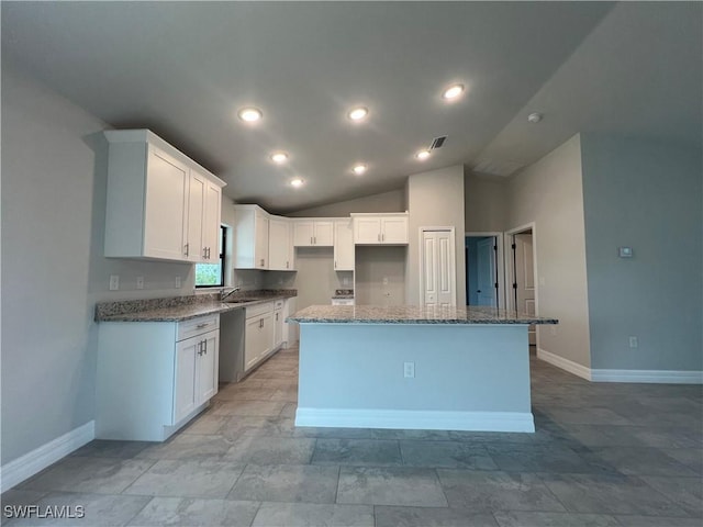 kitchen with stainless steel dishwasher, stone counters, white cabinets, a kitchen island, and lofted ceiling