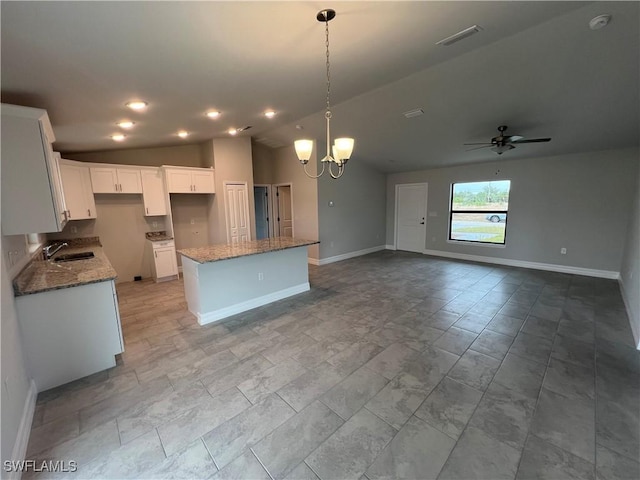 kitchen featuring pendant lighting, a center island, white cabinets, ceiling fan with notable chandelier, and vaulted ceiling