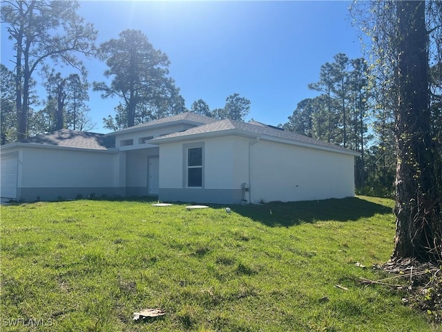 back of house with a garage, stucco siding, and a yard