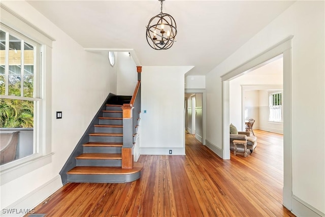 staircase with wood-type flooring and a chandelier