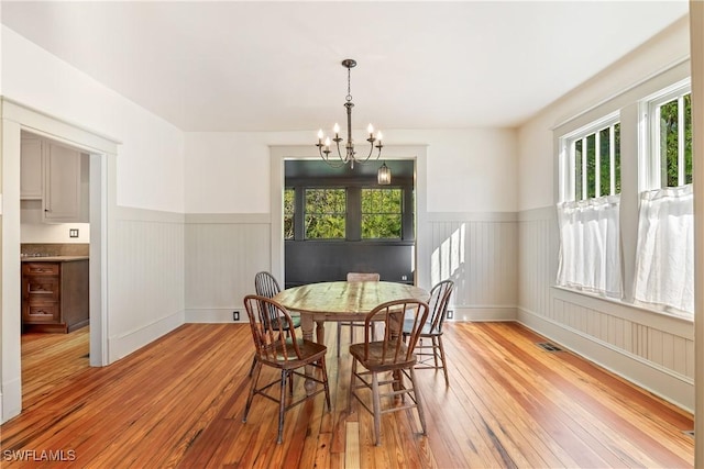 dining area with light hardwood / wood-style flooring and an inviting chandelier