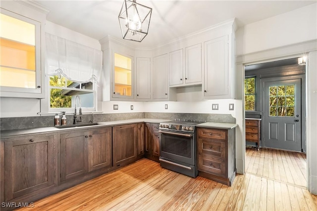 kitchen featuring light hardwood / wood-style floors, sink, stainless steel range with electric cooktop, and hanging light fixtures