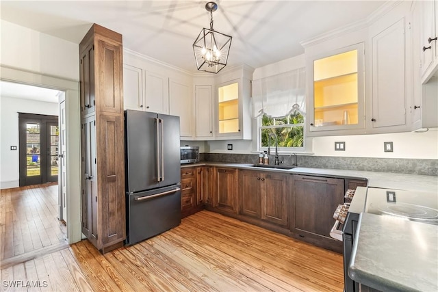 kitchen with white cabinetry, sink, light hardwood / wood-style floors, pendant lighting, and appliances with stainless steel finishes