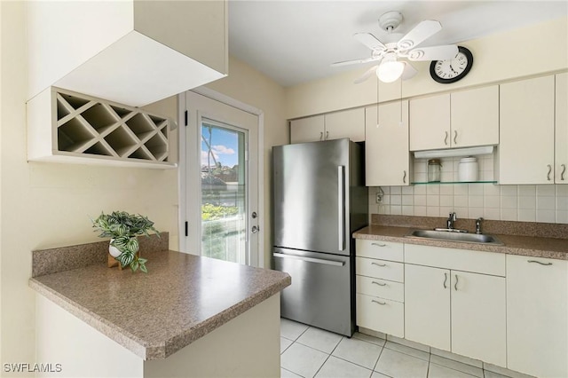 kitchen with ceiling fan, sink, backsplash, stainless steel fridge, and light tile patterned floors