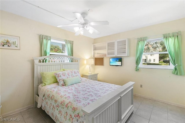 tiled bedroom featuring multiple windows and ceiling fan