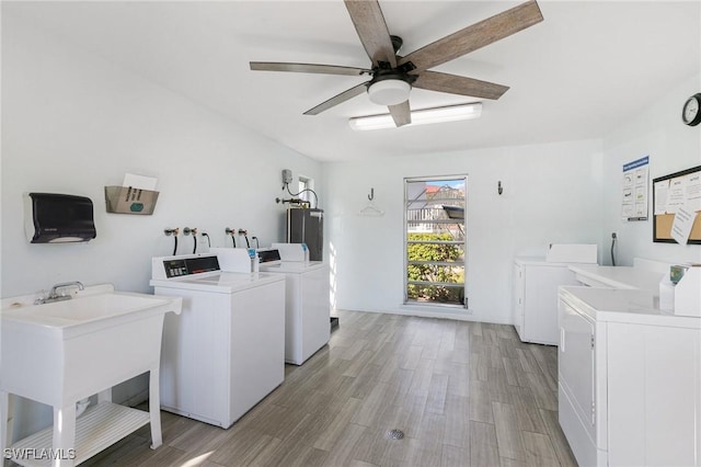 laundry area with light hardwood / wood-style floors, washing machine and dryer, sink, and gas water heater