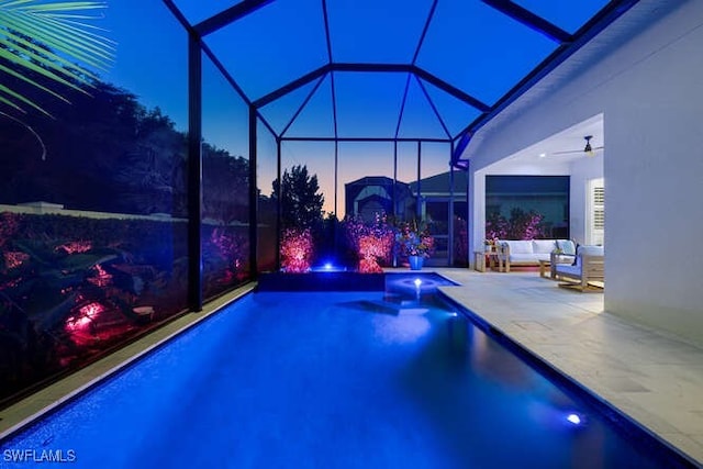 pool at dusk featuring a patio, an outdoor hangout area, ceiling fan, and glass enclosure