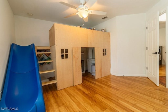 unfurnished bedroom with ceiling fan, washer / dryer, and light hardwood / wood-style flooring