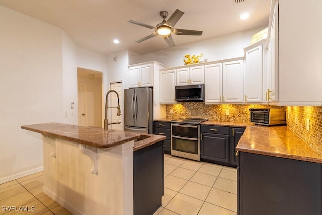 kitchen with a breakfast bar, a kitchen island, white cabinetry, and appliances with stainless steel finishes