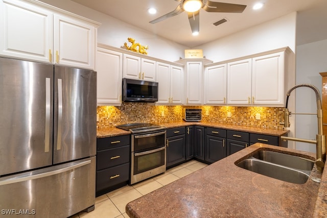 kitchen featuring sink, stainless steel appliances, light tile patterned floors, decorative backsplash, and white cabinets