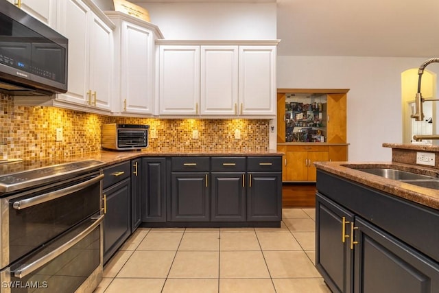 kitchen featuring white cabinets, light tile patterned floors, appliances with stainless steel finishes, and tasteful backsplash