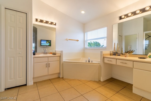 bathroom featuring tile patterned flooring, vanity, a relaxing tiled tub, and vaulted ceiling