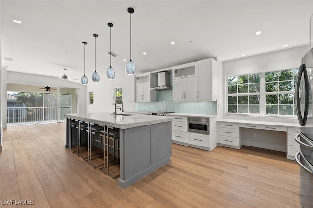 kitchen with pendant lighting, white cabinets, wall chimney exhaust hood, ceiling fan, and decorative backsplash