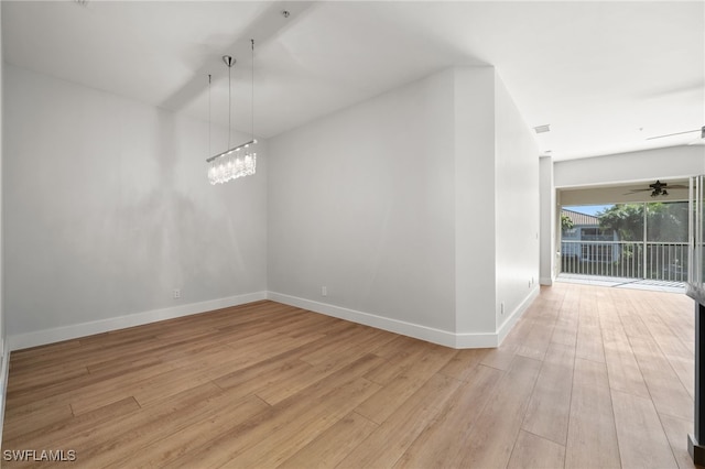 empty room with ceiling fan with notable chandelier and light wood-type flooring