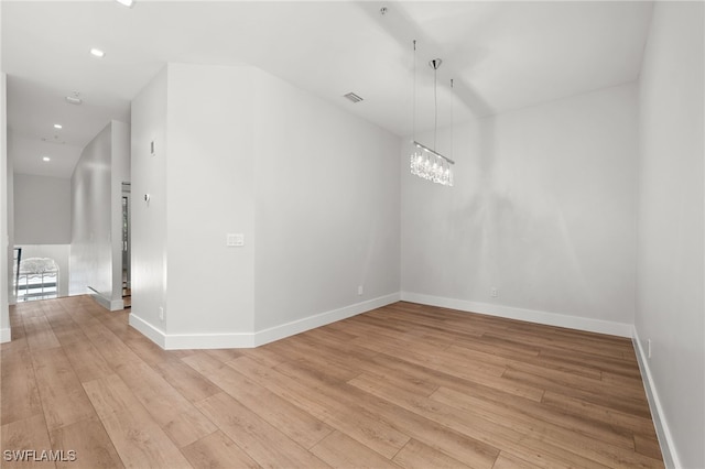 empty room featuring light hardwood / wood-style flooring and a notable chandelier