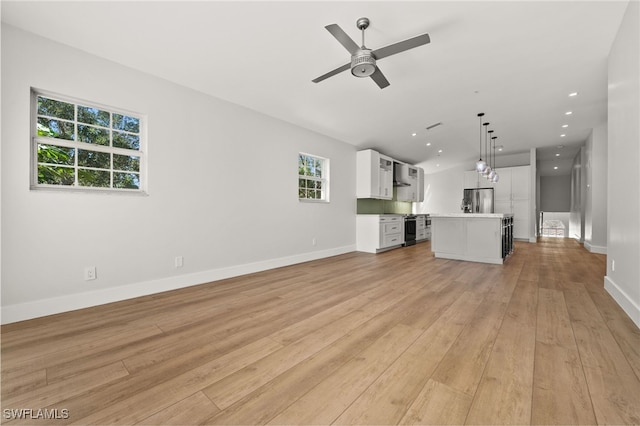 unfurnished living room featuring ceiling fan and light hardwood / wood-style floors