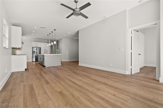 unfurnished living room with light hardwood / wood-style flooring, ceiling fan, and sink