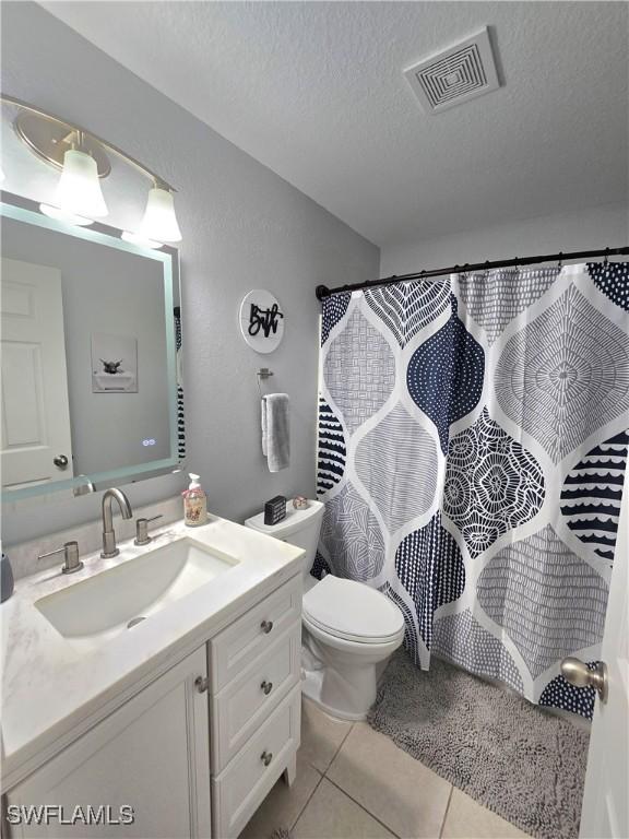 bathroom featuring tile patterned flooring, toilet, a textured ceiling, vanity, and a shower with shower curtain