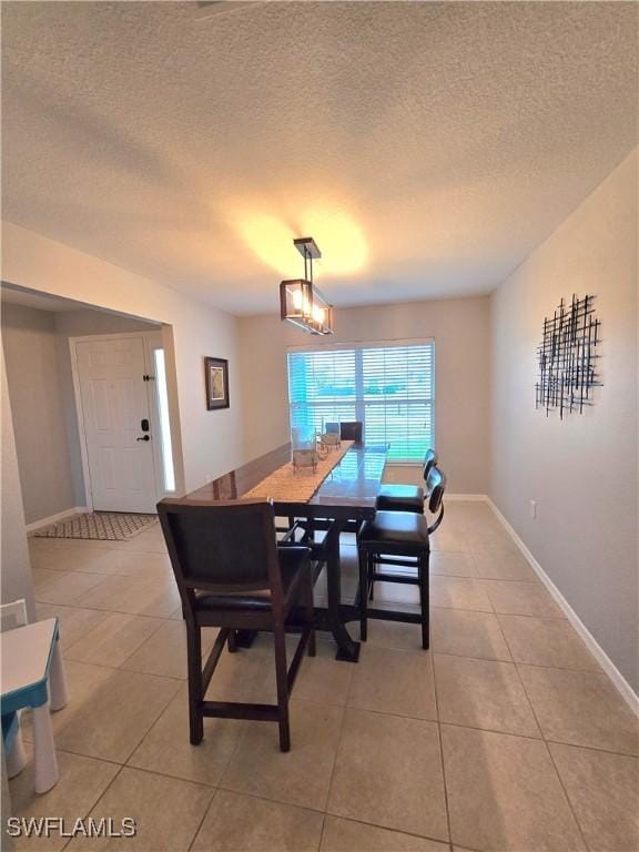 tiled dining area featuring a chandelier and a textured ceiling