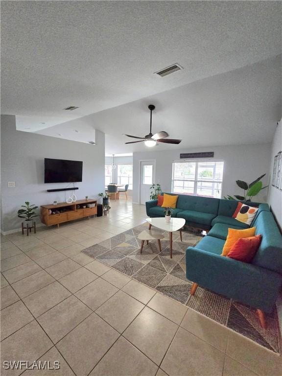 tiled living room featuring a wealth of natural light, a textured ceiling, and lofted ceiling