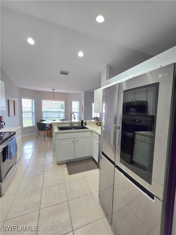 kitchen featuring white cabinets, stainless steel appliances, sink, kitchen peninsula, and light tile patterned floors