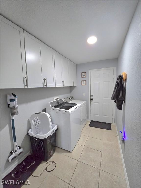 washroom featuring cabinets, separate washer and dryer, and light tile patterned floors