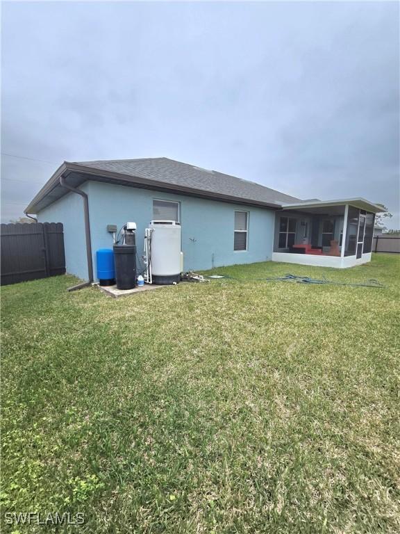 back of property with a sunroom and a yard