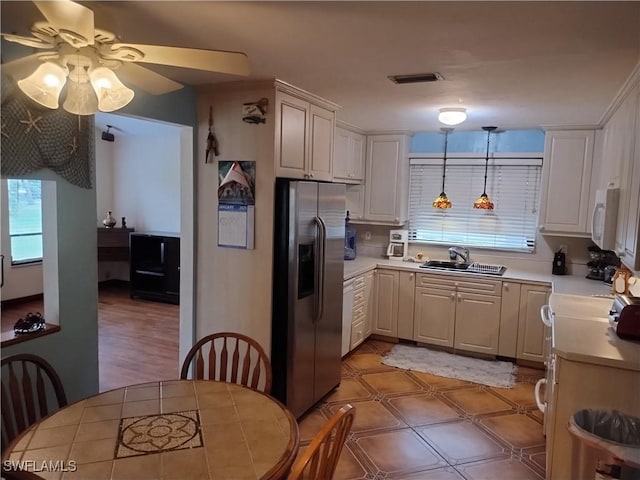 kitchen featuring white cabinets, stainless steel refrigerator with ice dispenser, hanging light fixtures, and sink