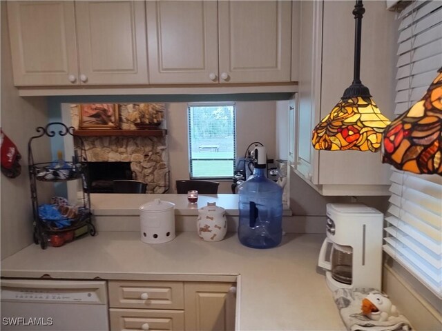 kitchen with decorative light fixtures, white dishwasher, a stone fireplace, and white cabinetry