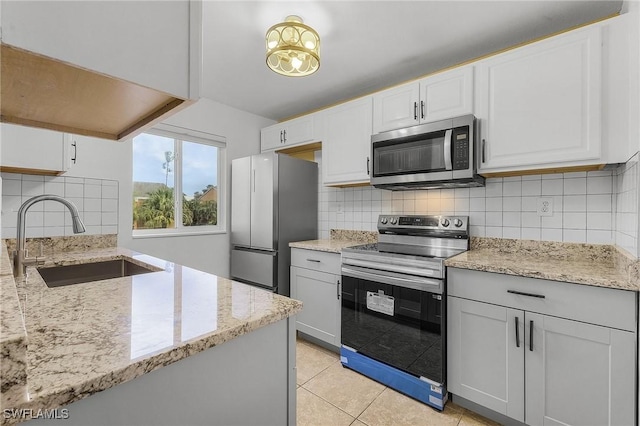 kitchen with light stone counters, appliances with stainless steel finishes, decorative backsplash, and a sink