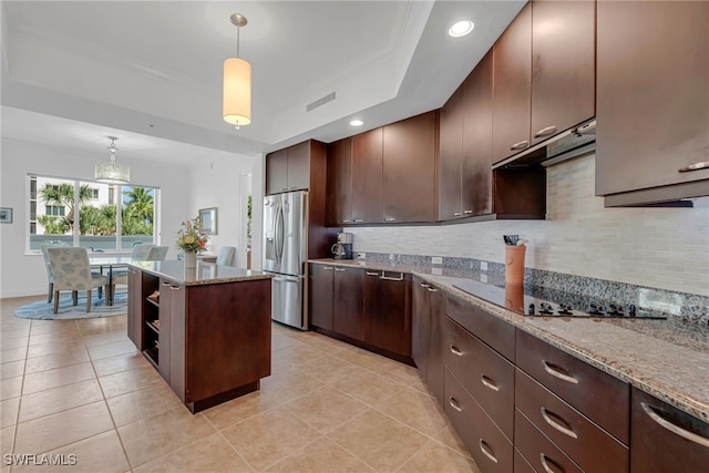 kitchen with decorative light fixtures, backsplash, a tray ceiling, and stainless steel refrigerator with ice dispenser