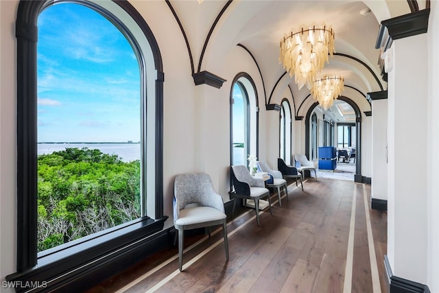 interior space with a chandelier, arched walkways, hardwood / wood-style flooring, and a water view