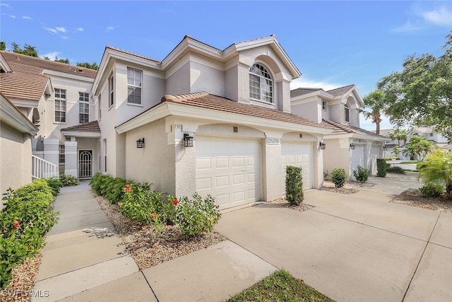 view of front of house with stucco siding, driveway, an attached garage, and a tile roof