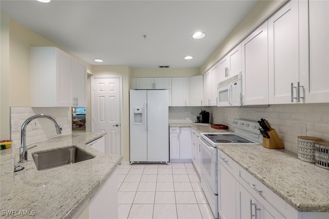 kitchen with sink, light stone counters, white cabinets, and white appliances