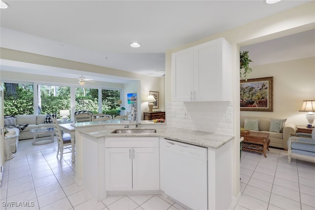 kitchen with light stone counters, white cabinets, kitchen peninsula, and dishwasher