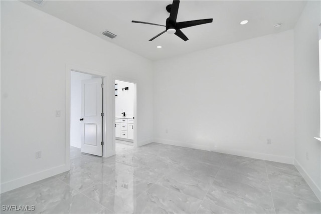 empty room with marble finish floor, a ceiling fan, visible vents, and baseboards