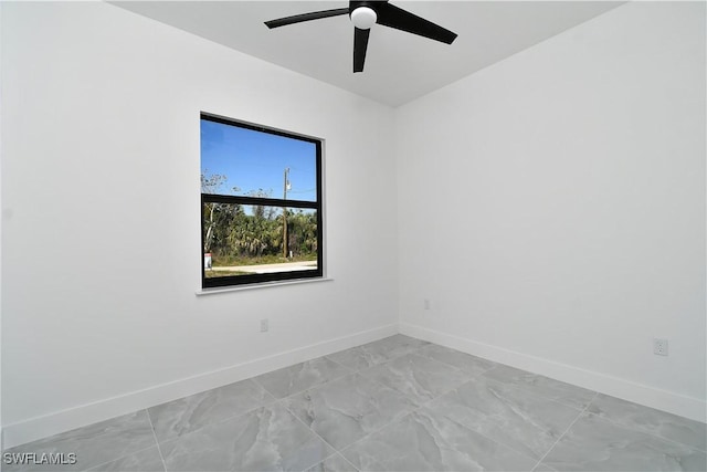 unfurnished room with ceiling fan, marble finish floor, and baseboards